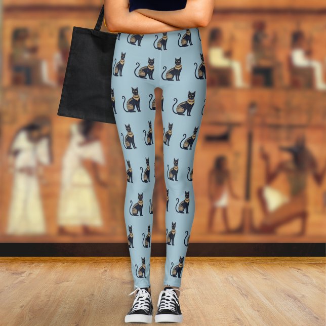 Legging Gato Negro Egípcio Padrado Azul Derrante (A pair of light blue leggings with a pattern of Egyptian-style black and faux gold cats)