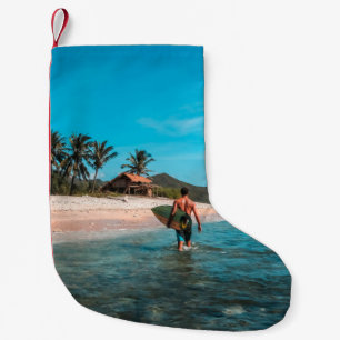 Meia De Natal Pequena Homem que segura conselho de surf no corpo de águ