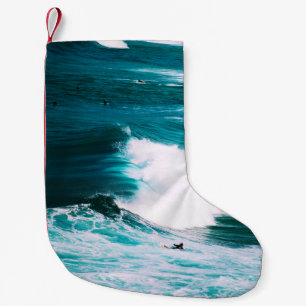 Meia De Natal Pequena Pessoa no surfboard com ondas oceânicas