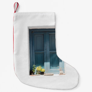MEIA DE NATAL PEQUENA PORTA DE MADEIRA AZUL NA PAREDE CONCRETA BRANCA