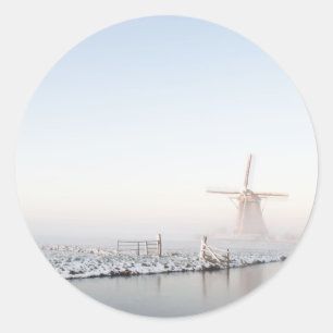 Moinho de vento na neve na etiqueta redonda do