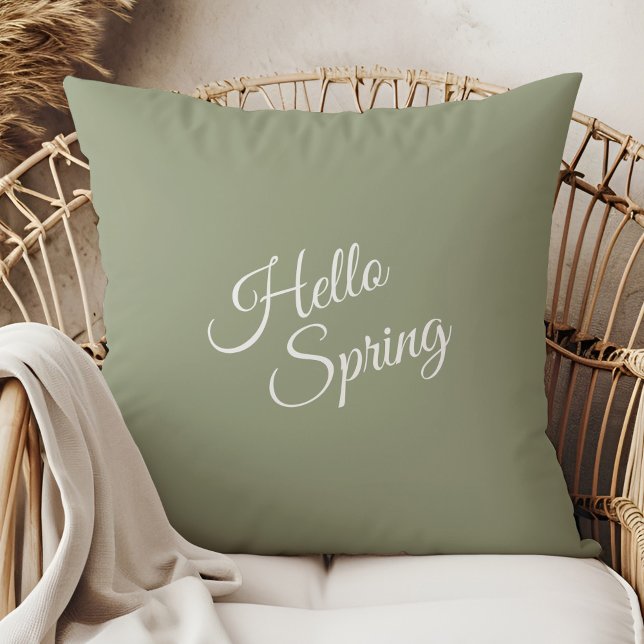 Olá Almofada de Lançamento Verde Sage Primavera (Hello Spring Sage Green Throw Pillow in a  boho neutral rattan armchair.)