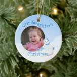 Ornamento De Cerâmica Grandaughter's 1st Christmas Snowman Round Photo<br><div class="desc">Your granddaughter will cherish her 1st christmas snowman ornament with her photo. This adorable showgirl is decked out in fuzzy blue hat, scarf and mittens as delicate snowflakes fall through the winter sky. Add photo to front and name and year to the back of the ornament using the template provided....</div>