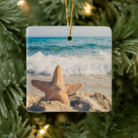 Ornamento De Cerâmica Starfish em uma fotografia de Sandy Beach<br><div class="desc">Um ornamento com uma foto cênica. Um grande peixe-estrela colocado em pé numa praia arenosa. Um belo mar azul com ondas de surf branco no fundo.</div>
