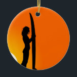 Ornamento De Cerâmica Surfista Sunset Girl com surfboard<br><div class="desc">Uma legal design de uma silhueta de uma surfista segurando seu surfboard contra um pôr de sol laranja brilhante. Esta praia,  a design de inspiração de Summer é brilhante e vibrante e para amantes do surfe e do estilo de vida na praia em todo o mundo.</div>