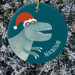 Ornamento De Cerâmica Tyrannosaurus Rex Christmas Santa Hat Personalizad<br><div class="desc">Um dinossauro tiranossauro divertido vestindo um chapéu de Natal para Papai Noel,  com um nome de fonte moderno que pode ser mudado para personalizar. Arte original de Nic Squirrell.</div>