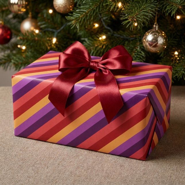 Papel de embrulho com listras vermelhas roxas e do (Bold Retro Red Purple Gold Stripes Wrapping Paper wrapped around a present under a Christmas tree.)