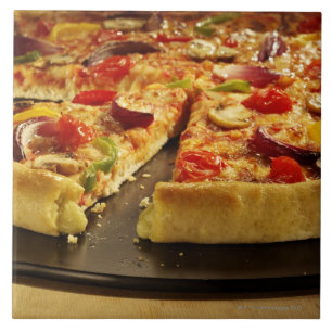 Pizza vegetal cortada na bandeja preta na madeira