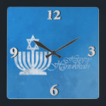Relógio Quadrado Bênçãos do Menorah<br><div class="desc">10, 75" x 10, 75" pulso de disparo acrílico com uma imagem de um menorah azul pálido e branco cobriram com uma estrela de David no azul sujo. Veja a coleção inteira do pulso de disparo de Hanukkah na seção dos FERIADOS.</div>
