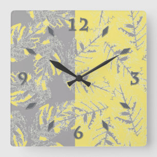 Relógio Quadrado Cinzas e folhas amarelas sobre fundo listrado.
