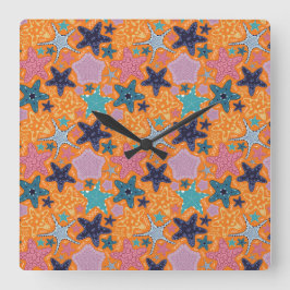 Relógio Quadrado Fios coloridos com fundo cor de laranja.