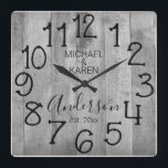 Relógio Quadrado Nome da Família Personalizada da Casa Farmônica de<br><div class="desc">Um design rústico, único, personalizado, de um tipo, apresenta um fundo de madeira falsa com as palavras "MICHAEL & KAREN Anderson est. 20XX" em tipografia negra. Personalize este relógio adicionando suas próprias informações pessoais. Faz um casamento excelente, aniversário ou presente de inauguração. Clique em "personalizar este modelo" para alterar os...</div>