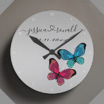 Relógio Redondo Presente de casamento para as Cinzas da Silvery Pe<br><div class="desc">Linda conexão com o relógio da cinza de prata do amor celebrando um casal e seu amor. Personalizado com os nomes dos casais escritos em cursivo e ligados a um coração suave. É também personalizado com uma data personalizada. Decorado com uma ilustração fofinha de duas borboletas, uma roxa azul. Trendy,...</div>