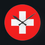 Relógio Redondo sinalizador de suiça<br><div class="desc">A bandeira da Suiça (alemã: Schweizerfahne; francesa: drapeau de la Suisse; italiana: bandiera svizzera; Romansh: bandiera de la Svizra) exibe uma cruz branca no centro de um campo vermelho quadrado. A cruz branca é conhecida como a cruz suíça.</div>