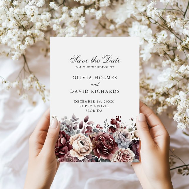 Reserve A Data Boho Borgonha & Verde Sage Floral Salve o Dia (Boho Burgundy & Sage Green Floral Save the Date in hands next to tiny white flowers.)