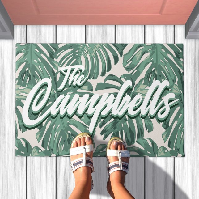 Tapete Porta do Sobrenome de Script de Folhas Tropicais V (Doormat with pattern of sage green tropical leaves. Overlaid is your family last name)