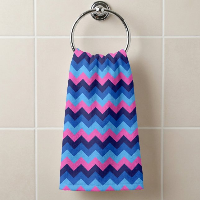 Toalha de mão com padrão de Chevron rosa azul frio (Cool Blue Pink Chevron Pattern Hand Towel hanging on a towel ring in a bathroom.)