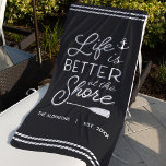 Toalha De Praia A Vida Personalizada É Melhor Na Margem<br><div class="desc">Atualize sua configuração ao ar livre na sua zona costeira com esta linda toalha de praia personalizada com a frase "A vida é melhor na praia" em letras brancas acentuadas com uma âncora e um remos. Personalize com seu nome de família e/ou ano estabelecido abaixo.</div>
