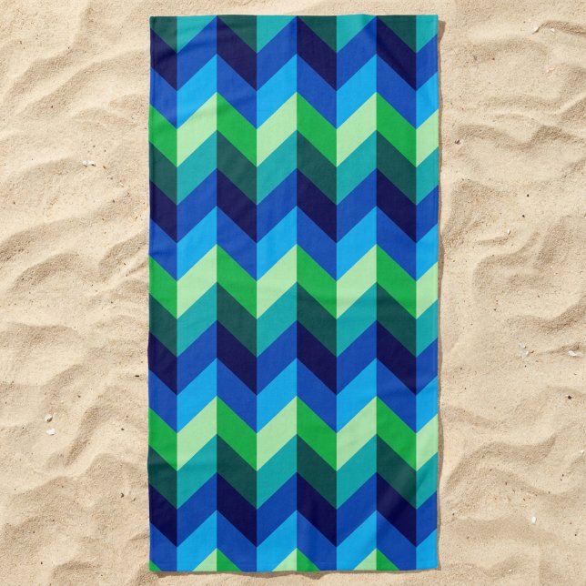 Toalha de Praia com Ombre Chevrons Azul Verde (Blue Green Ombre Chevrons Beach Towel lying in the sand.)