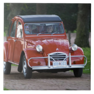 Um velho Citroen 2CV vermelho com uma mulher sorri